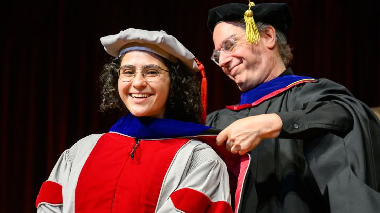 MAS student receives hood on stage