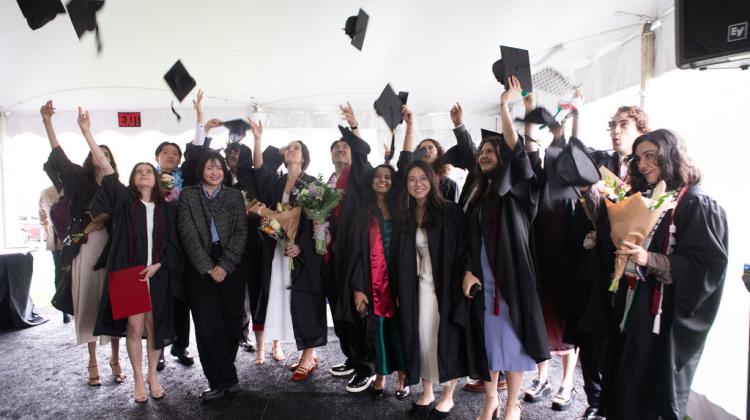 Group of graduates toss graduation caps in the air 